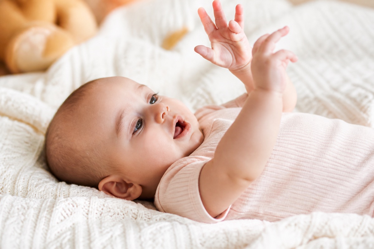 Bébé de quatre mois éveillé et curieux, observant ses mains à la lumière du jour